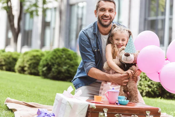 Father and daughter with teddy bear playing tea party at lawn — Stock Photo