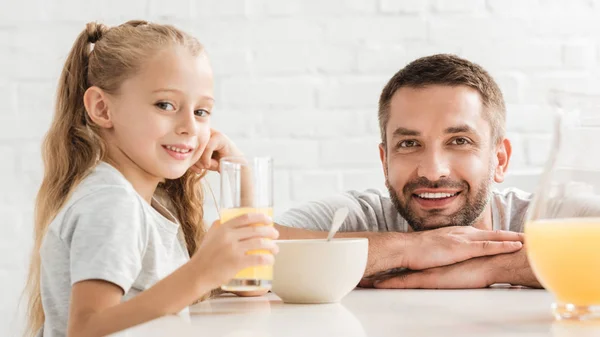 Vater und Tochter trinken Orangensaft und blicken in die Kamera — Stockfoto
