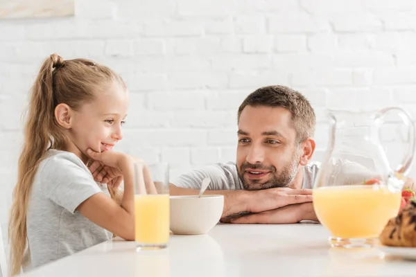 Батько і дочка п'ють апельсиновий сік на кухні — стокове фото