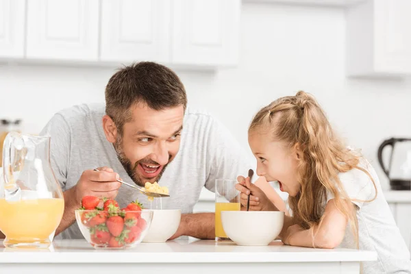 Padre e hija desayunando y mirándose - foto de stock