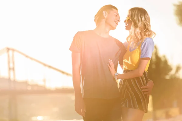 Young couple hugging and going to kiss on river beach in evening — Stock Photo