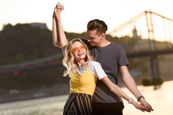 Young couple holding hands and having fun on river beach in evening — Stock Photo