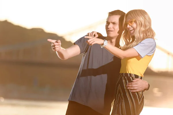 Young couple pointing on something at river beach in evening — Stock Photo