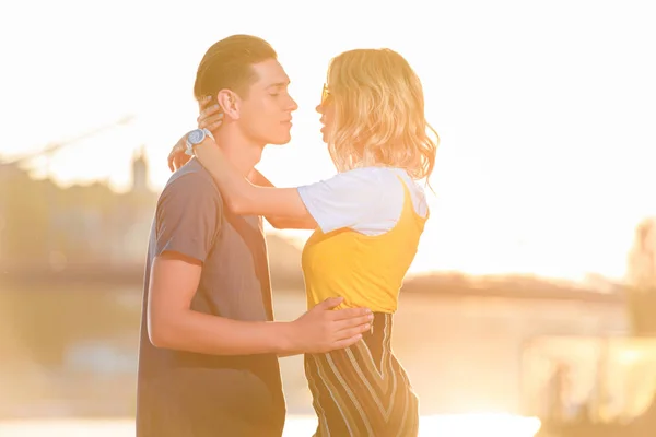 Vista lateral de pareja joven que va a besarse en la playa del río por la noche - foto de stock