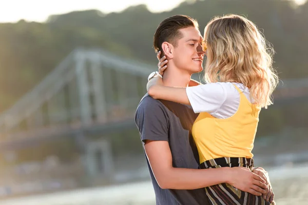 Vista lateral de pareja heterosexual que va a besarse en la playa del río por la noche - foto de stock