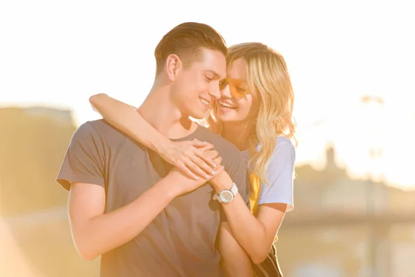 Novia feliz abrazando novio en la playa del río durante la puesta del sol - foto de stock