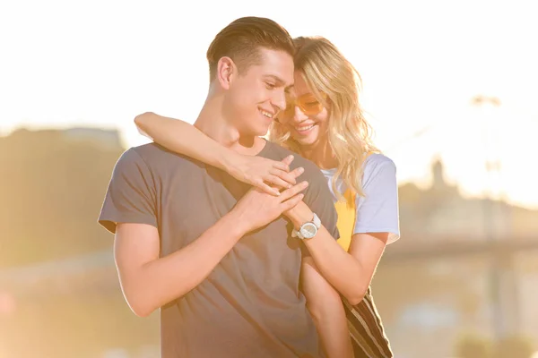 Girlfriend hugging boyfriend on river beach in evening and they holding hands — Stock Photo