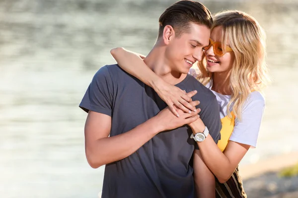 Novia abrazando novio y ellos tocando con frentes en la playa del río por la noche - foto de stock