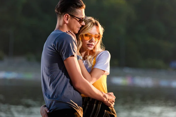 Jeune couple câlin sur la plage de la rivière dans la soirée — Photo de stock