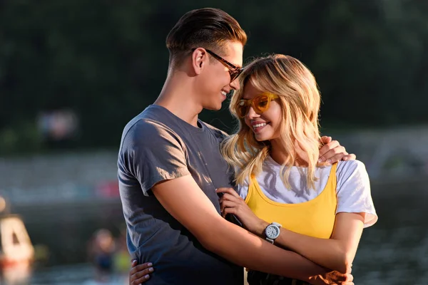 Sorridente giovane coppia coccole sulla spiaggia del fiume in serata — Foto stock