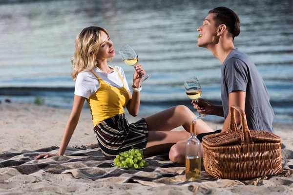 Jeune couple s'amusant au pique-nique sur la plage de la rivière en soirée — Photo de stock