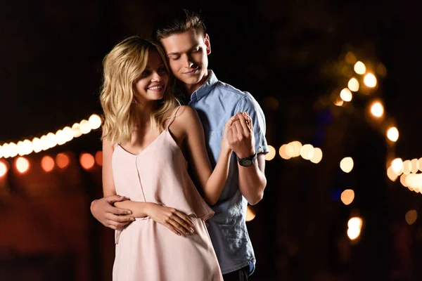 Boyfriend hugging girlfriend on river beach in evening — Stock Photo