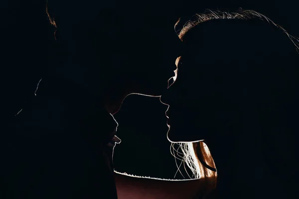 Silhouettes de jeune couple tendre dans l'obscurité — Photo de stock