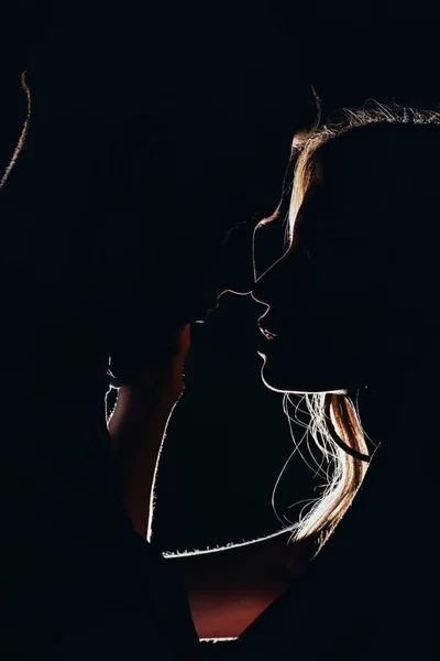 Silhouettes of young tender couple going to kiss in dark — Stock Photo