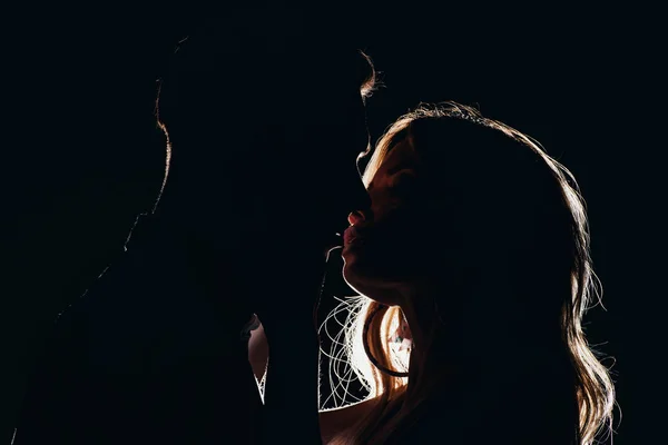 Silhouettes de couple hétérosexuel sensuel embrasser dans l'obscurité — Photo de stock