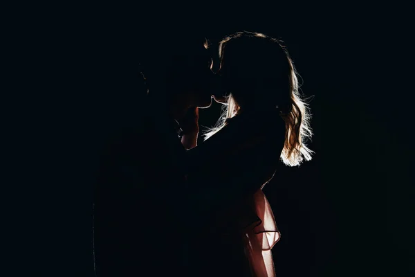 Silhouettes of passionate couple kissing in dark — Stock Photo