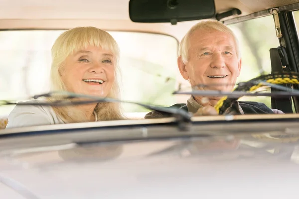 Marido y mujer mayores sonriendo en coche beige - foto de stock