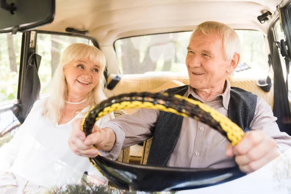 Bella coppia anziana sorridente e guida auto beige — Foto stock