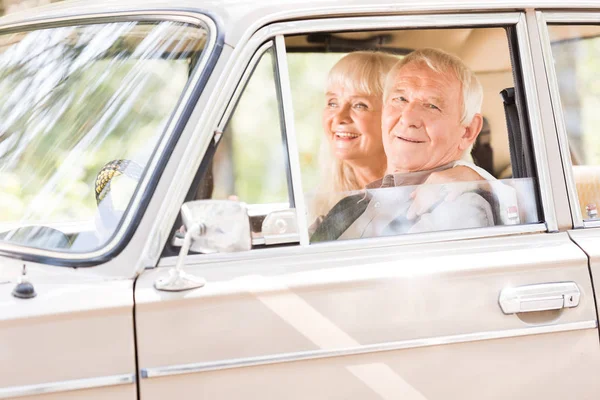 Mujer mayor abrazando hombre sonriente en coche beige - foto de stock