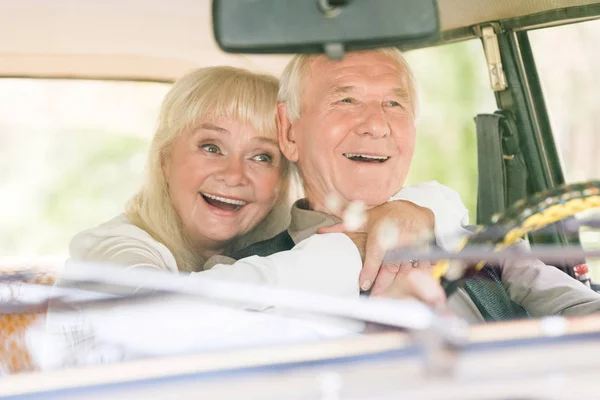 Vue de face de belle femme âgée excitée étreignant l'homme dans la voiture rétro — Photo de stock