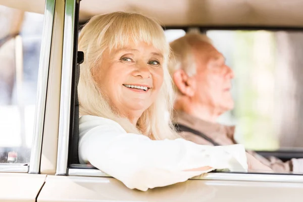 Vista laterale di marito e moglie anziani in auto d'epoca — Foto stock