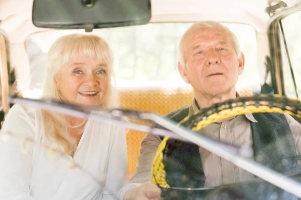Vista attraverso il parabrezza di marito e moglie anziani seduti in auto d'epoca — Foto stock
