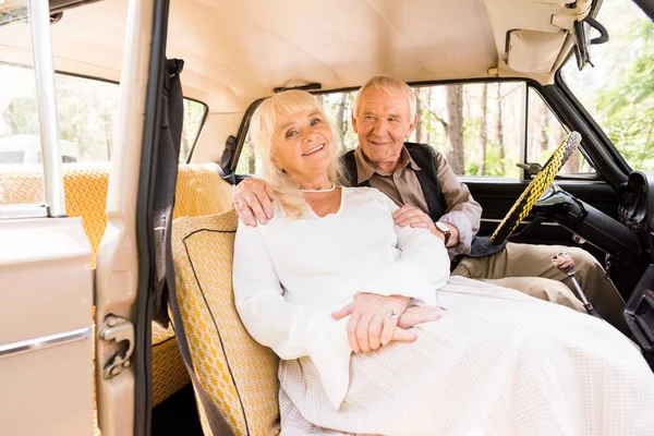 Hombre mayor abrazando a la mujer en coche beige - foto de stock