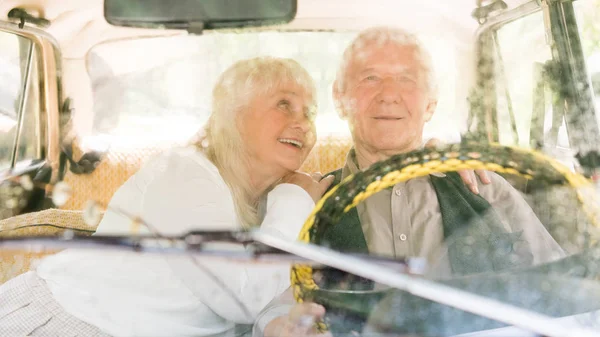 Vista attraverso il parabrezza della coppia anziana seduta in auto retrò — Foto stock