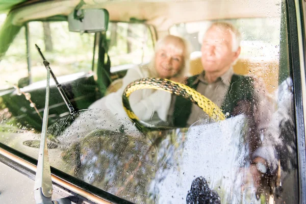 Vista attraverso il parabrezza della coppia anziana seduta in auto beige, messa a fuoco selettiva — Foto stock