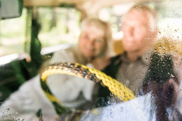 View through windshield of senior man and woman sitting in vintage car — Stock Photo