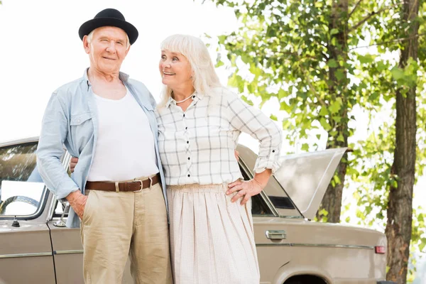 Élégant couple de personnes âgées debout près de voiture beige — Photo de stock
