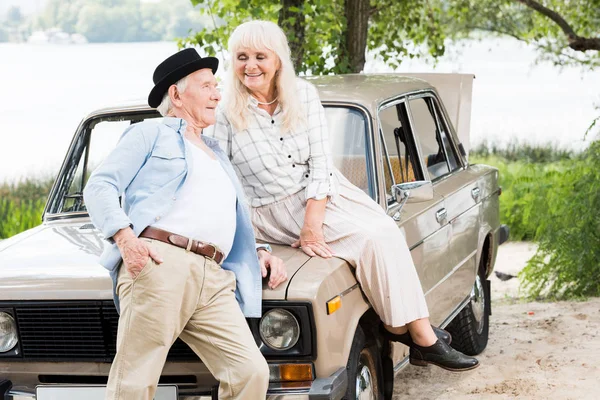 Senior homme près de femme assis sur la voiture rétro — Photo de stock