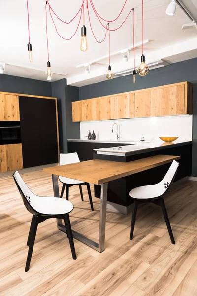 Intérieur de la salle à manger moderne et lumineuse avec table et chaises en bois confortables — Photo de stock