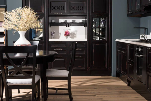 Интерьер современной столовой с черной мебелью и вазой из сушеных цветов на столе — стоковое фото