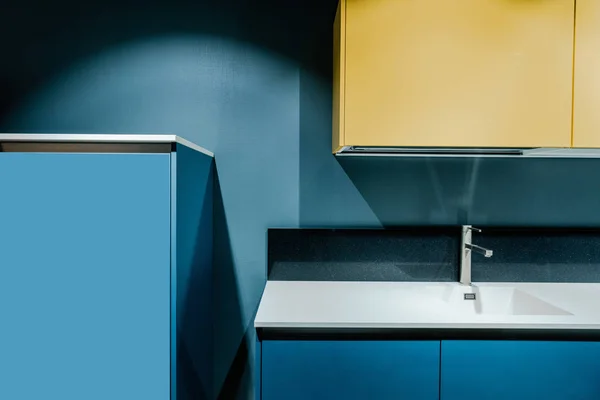 Part of contemporary kitchen with blue and yellow shelves and tap — Stock Photo