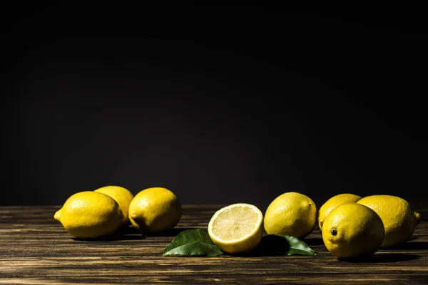 Saftige gelbe Zitronen auf Holztisch mit schwarzem Hintergrund — Stockfoto