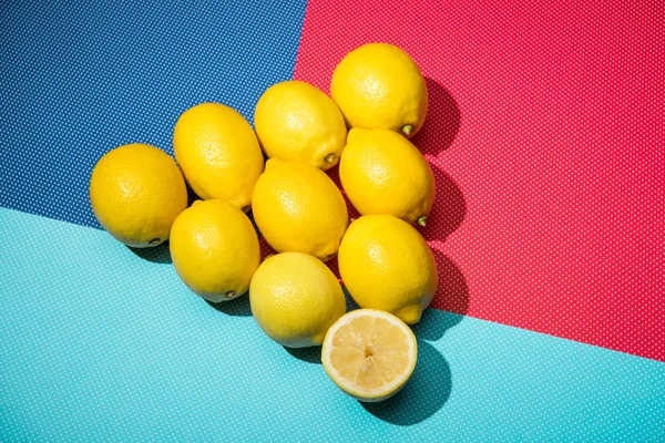 Figura de limones en triángulo sobre fondo azul, turquesa y rosa - foto de stock
