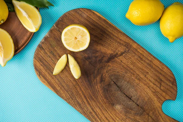 Vista dall'alto di limoni gialli freschi su tagliere di legno su sfondo turchese — Foto stock