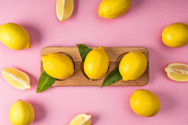 Top view of fresh yellow lemons on wooden board on pink background — Stock Photo