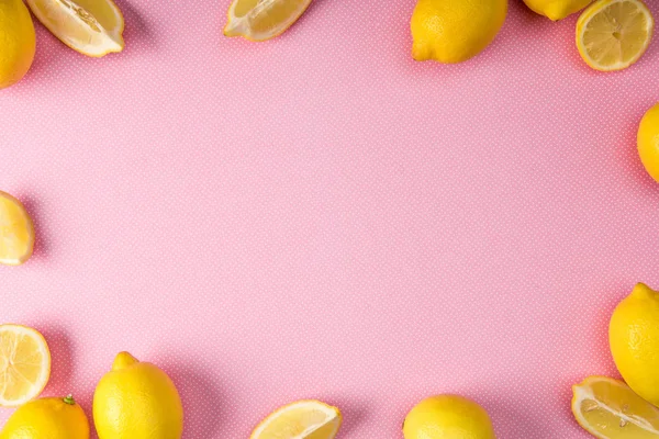 Vista superior del marco hecho de limones amarillos frescos sobre fondo rosa - foto de stock