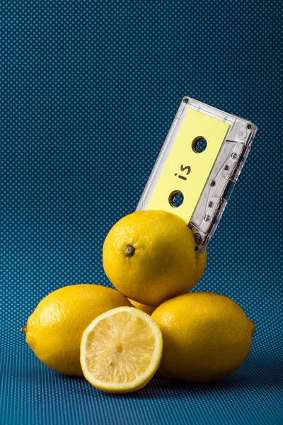 Fresh yellow lemons with vintage audio cassette on blue — Stock Photo