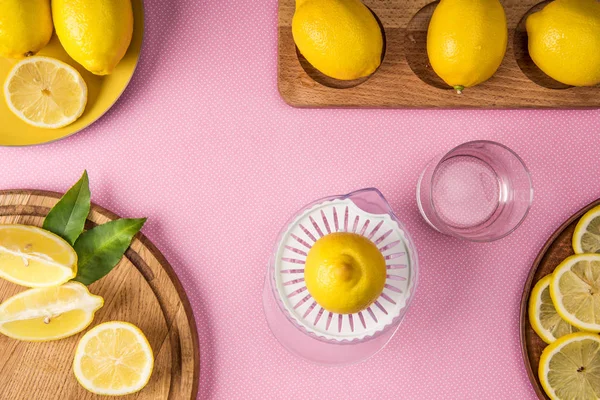 Top view of yellow lemons and juice squeezer on pink background — Stock Photo