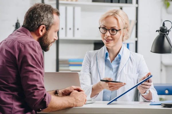 Patient hat Termin mit lächelndem Physiotherapeuten im Krankenhaus — Stockfoto