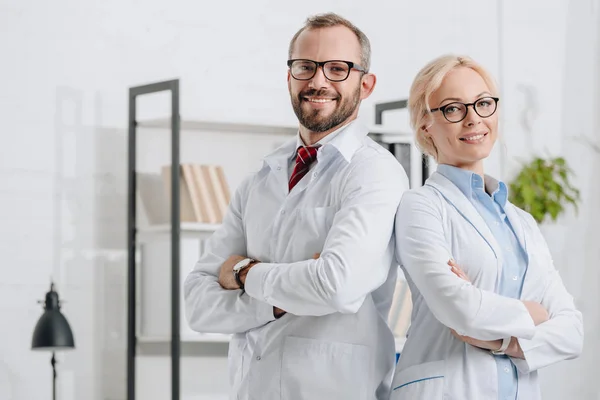 Portrait of smiling physiotherapists in white coats looking at camera in clinic — Stock Photo