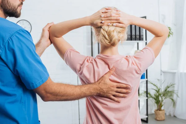 Cropped shot of physiotherapist doing massage to woman on massage table in hospital — Stock Photo