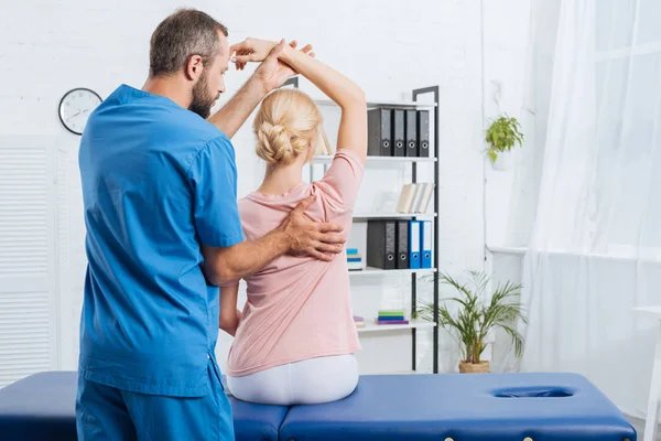 Physiothérapeute étirant le bras des patients sur la table de massage à l'hôpital — Photo de stock