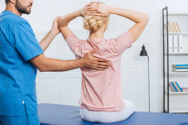 Teilansicht des Physiotherapeuten, der Frau auf Massagetisch im Krankenhaus massiert — Stockfoto