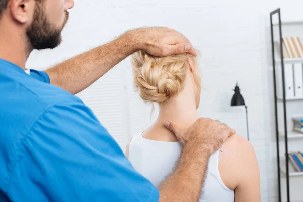 Partial view of chiropractor stretching neck of woman during appointment in hospital — Stock Photo