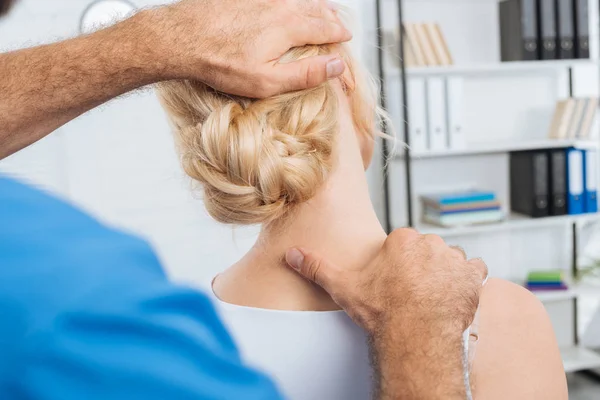 Partial view of chiropractor stretching neck of woman during appointment in hospital — Stock Photo