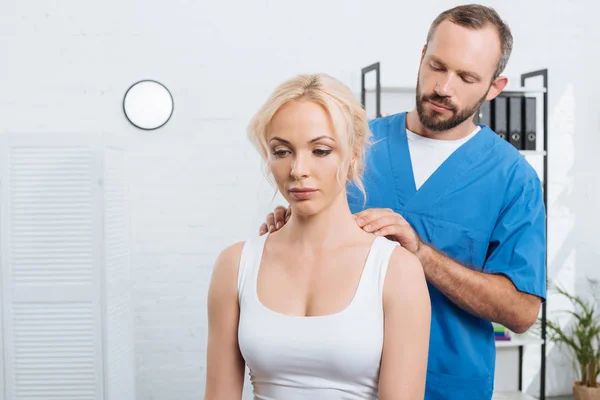 Портрет физиотерапевта, массирующего женские плечи в больнице — стоковое фото